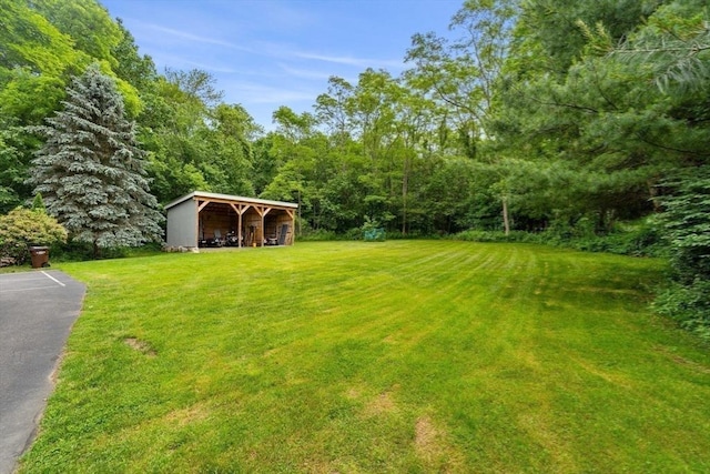 94 Kimball Rd, Amesbury, MA 01931 - view of green lawn featuring a pole building, a wooded view, and an outbuilding