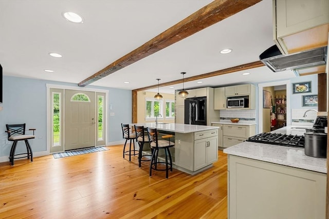 94 Kimball Rd, Amesbury, MA 01931 - kitchen featuring black refrigerator, stainless steel microwave, a kitchen bar, beamed ceiling, and light wood finished floors