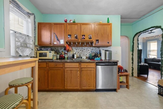 69 Conwell Ave, Somerville, MA 02144 - kitchen featuring dishwasher, white microwave, brown cabinets, arched walkways, and tasteful backsplash