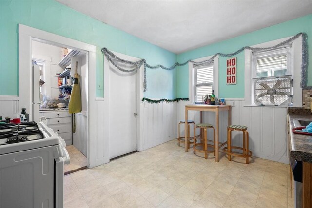 69 Conwell Ave, Somerville, MA 02144 - kitchen with range with gas cooktop, wainscoting, a decorative wall, and light floors