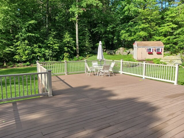 wooden deck with a storage shed and a lawn