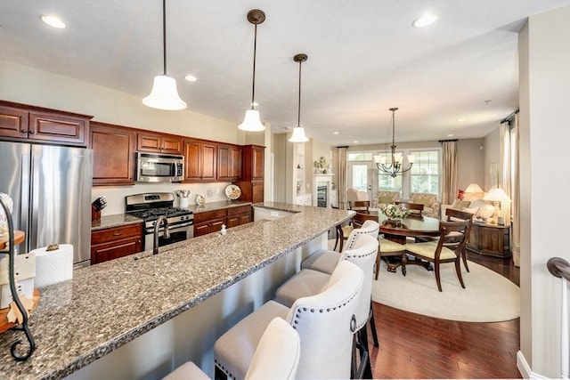 16 Twin Oaks Dr Unit 732, Mashpee, MA 02649 - kitchen featuring light stone counters, a kitchen breakfast bar, stainless steel appliances, dark wood-type flooring, and pendant lighting