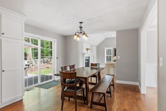 3 Chad Ln, Sterling, MA 01564 - dining space with light wood-style floors, a chandelier, vaulted ceiling, baseboards, and a glass covered fireplace