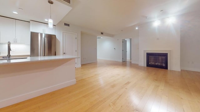 unfurnished living room featuring sink and light hardwood / wood-style floors