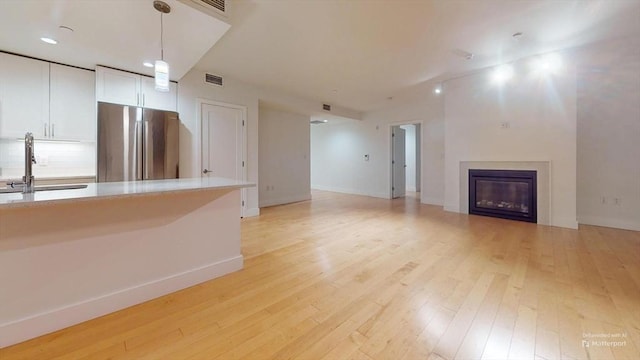 unfurnished living room with light hardwood / wood-style floors and sink