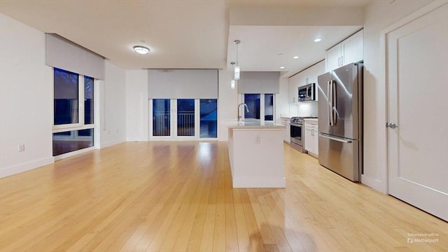 kitchen featuring white cabinetry, a kitchen island, stainless steel appliances, and light hardwood / wood-style floors