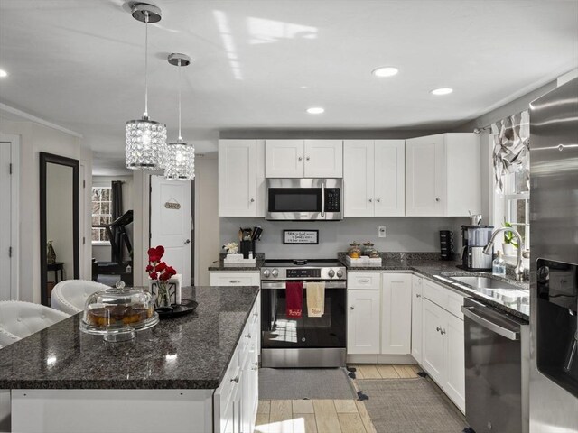kitchen featuring light wood-type flooring, a sink, appliances with stainless steel finishes, white cabinets, and a chandelier