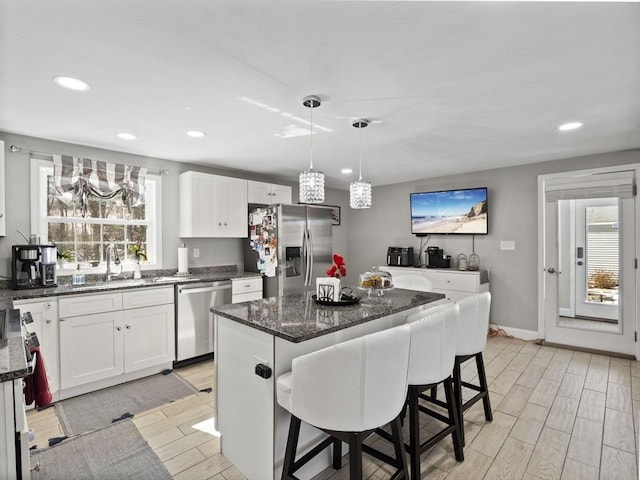 kitchen featuring wood finish floors, a sink, appliances with stainless steel finishes, a kitchen breakfast bar, and a chandelier