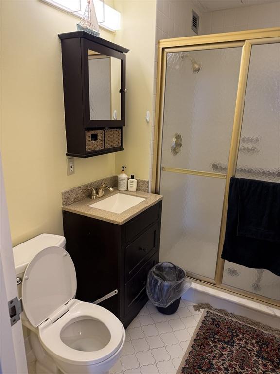 bathroom featuring toilet, walk in shower, and vanity