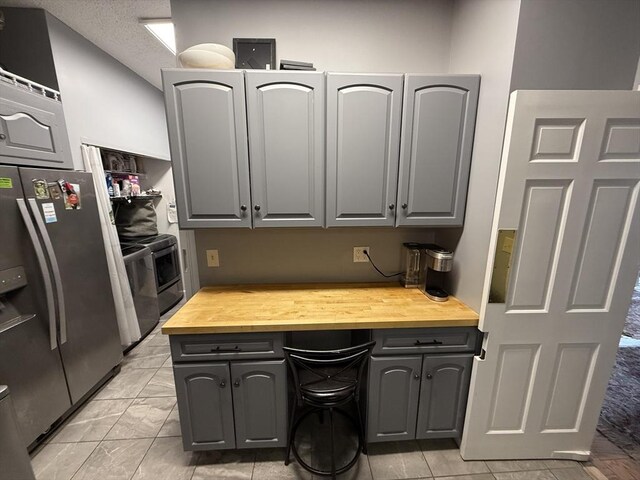 kitchen with butcher block counters, gray cabinetry, and stainless steel appliances