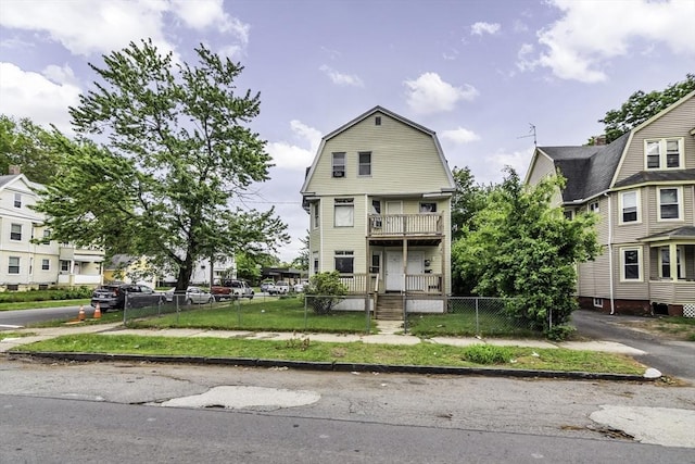 77-79 Grenada Ter, Springfield, MA 01108 - colonial inspired home featuring a fenced front yard, a balcony, a gambrel roof, and a gate