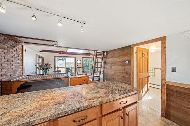 kitchen featuring wood walls, baseboard heating, light stone countertops, vaulted ceiling, and track lighting