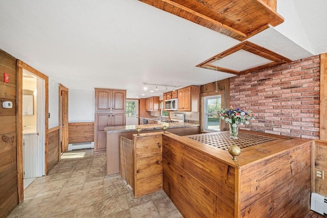 kitchen featuring baseboard heating, stainless steel microwave, wood walls, wainscoting, and a peninsula