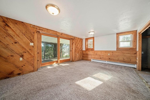 unfurnished living room with a baseboard heating unit, wood walls, and carpet floors