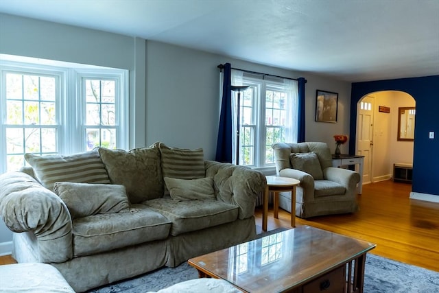 living room with arched walkways, wood finished floors, and baseboards