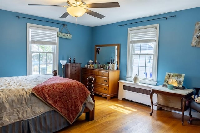bedroom featuring light wood-style floors, radiator, and ceiling fan
