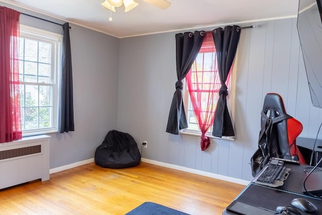 exercise area featuring radiator heating unit, wood finished floors, plenty of natural light, a ceiling fan, and crown molding