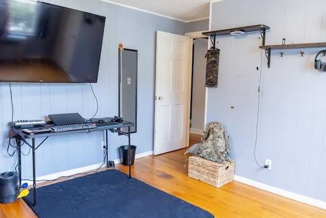 exercise area with wood finished floors, crown molding, and baseboards