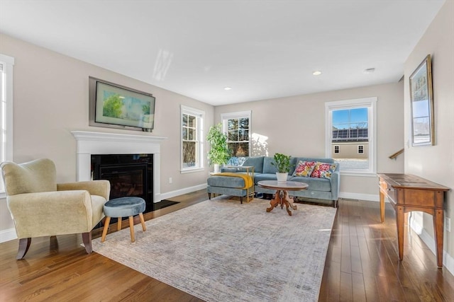 living area with recessed lighting, a premium fireplace, wood-type flooring, and baseboards