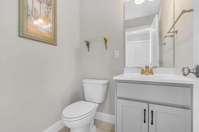 bathroom with tile patterned flooring, baseboards, vanity, and toilet