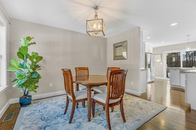 dining area with baseboards, visible vents, wood finished floors, a chandelier, and recessed lighting