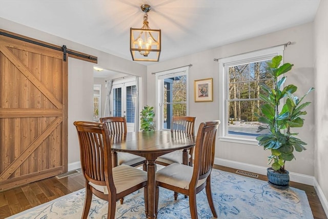 dining room featuring dark wood-style flooring, a healthy amount of sunlight, visible vents, and french doors