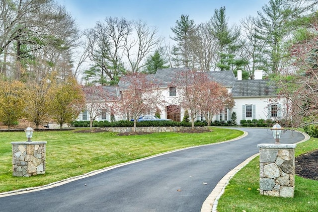42 Westerly Rd, Weston, MA 02493 - view of front of house featuring a front yard, a chimney, and driveway