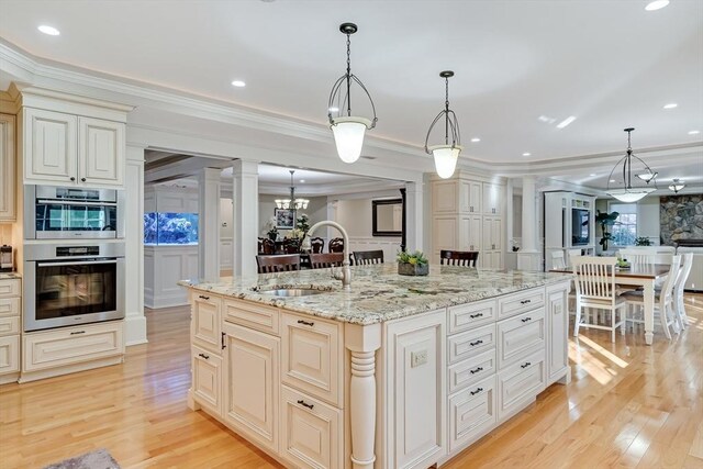 42 Westerly Rd, Weston, MA 02493 - kitchen featuring ornate columns, a sink, cream cabinetry, light wood-type flooring, and ornamental molding