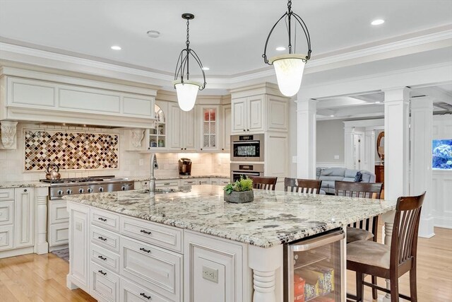 42 Westerly Rd, Weston, MA 02493 - kitchen with beverage cooler, ornate columns, a breakfast bar, light wood finished floors, and crown molding