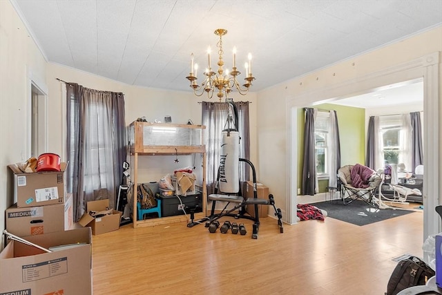 exercise area with a chandelier, wood finished floors, and ornamental molding