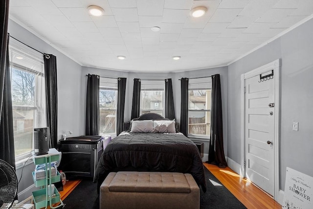 bedroom with recessed lighting, wood finished floors, crown molding, and baseboards