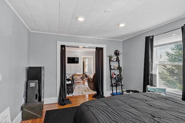 bedroom with baseboards, wood finished floors, recessed lighting, and ornamental molding