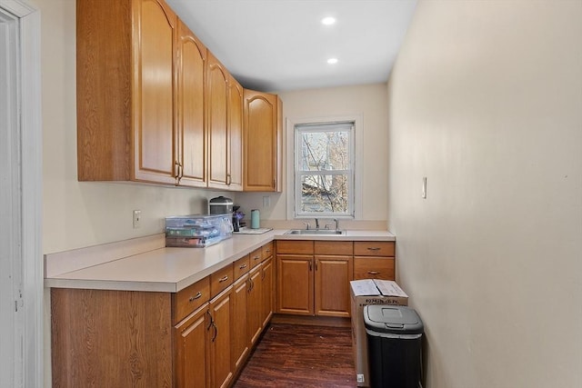 kitchen featuring light countertops, a sink, recessed lighting, and dark wood finished floors