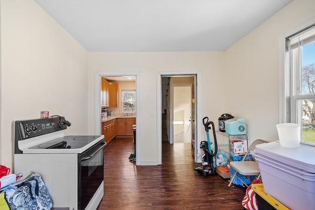 interior space featuring white electric stove, light countertops, a sink, brown cabinetry, and dark wood-style flooring