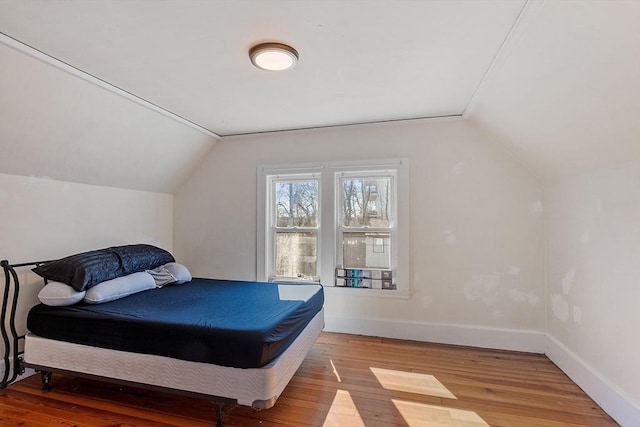 bedroom featuring lofted ceiling, light wood-style flooring, and baseboards