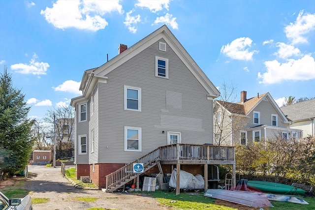 rear view of house featuring stairway, a wooden deck, and a chimney