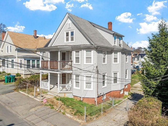 rear view of property with fence, a shingled roof, a chimney, and covered porch