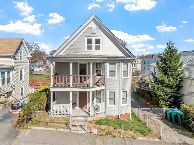 view of front of home with a gate, a fenced front yard, a balcony, and covered porch