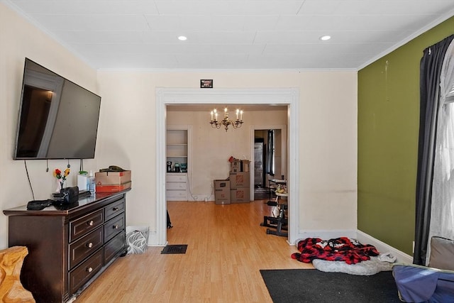 exercise room with a chandelier, light wood finished floors, baseboards, and ornamental molding