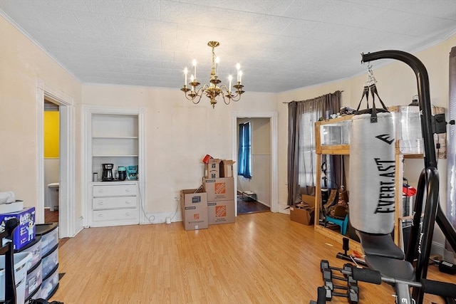 workout area with ornamental molding, built in features, a chandelier, and light wood-style floors