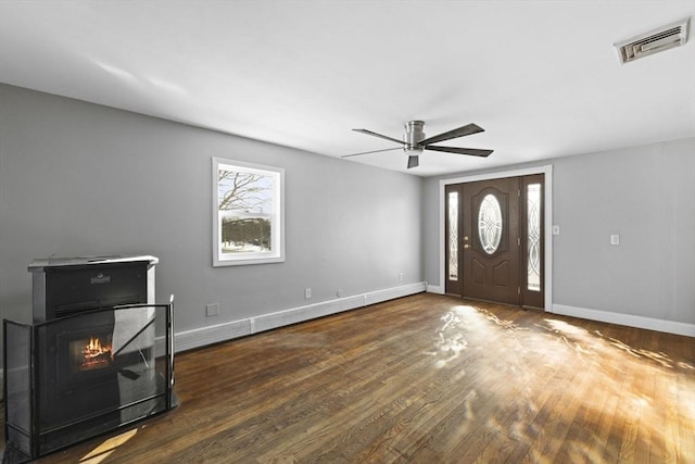 foyer entrance featuring ceiling fan, dark wood-type flooring, and a fireplace