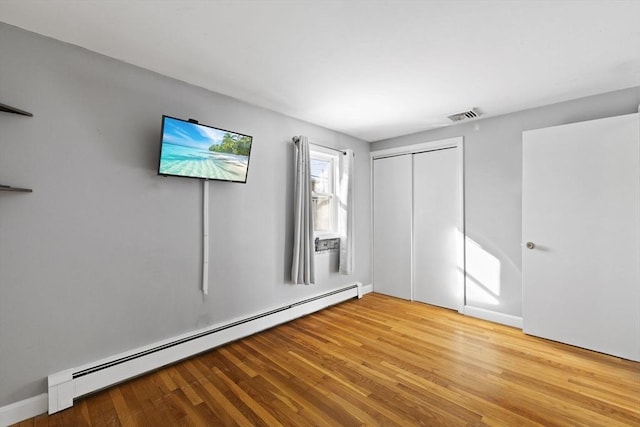 spare room featuring a baseboard heating unit and light wood-type flooring