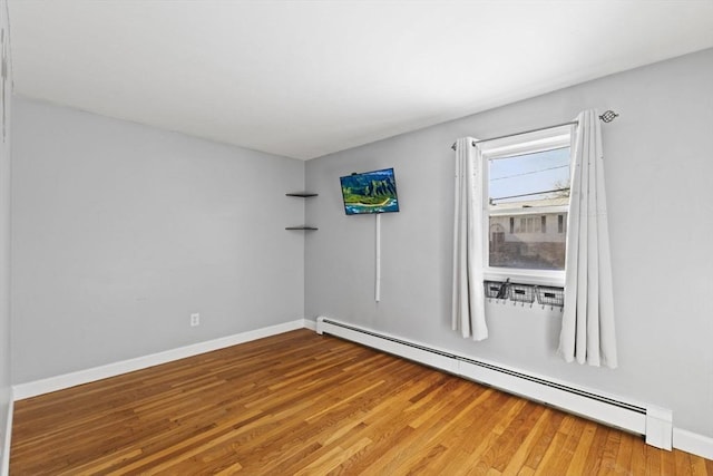 spare room with a baseboard radiator and hardwood / wood-style flooring