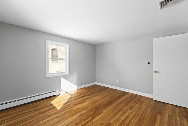 empty room featuring baseboard heating and wood-type flooring