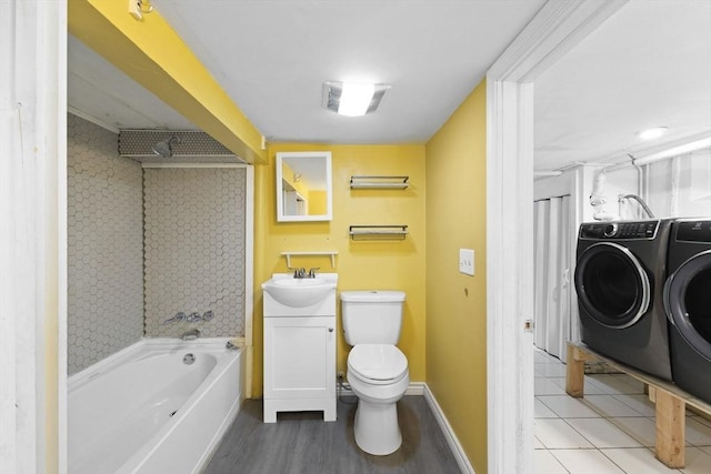 bathroom featuring toilet, washing machine and dryer, a tub to relax in, and vanity