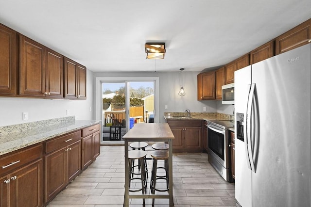 kitchen featuring pendant lighting, sink, light stone countertops, a breakfast bar, and stainless steel appliances