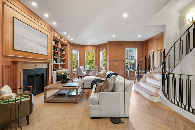 living room featuring built in shelves, wood walls, and light parquet floors