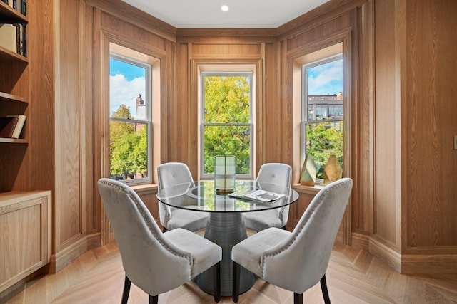 dining space with light parquet floors and wood walls