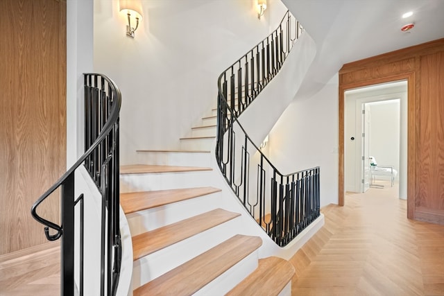 staircase featuring wooden walls and parquet floors