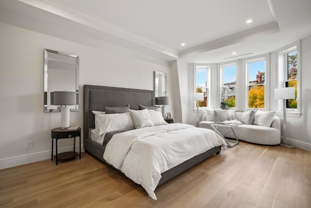 bedroom featuring ornamental molding, a raised ceiling, and hardwood / wood-style floors